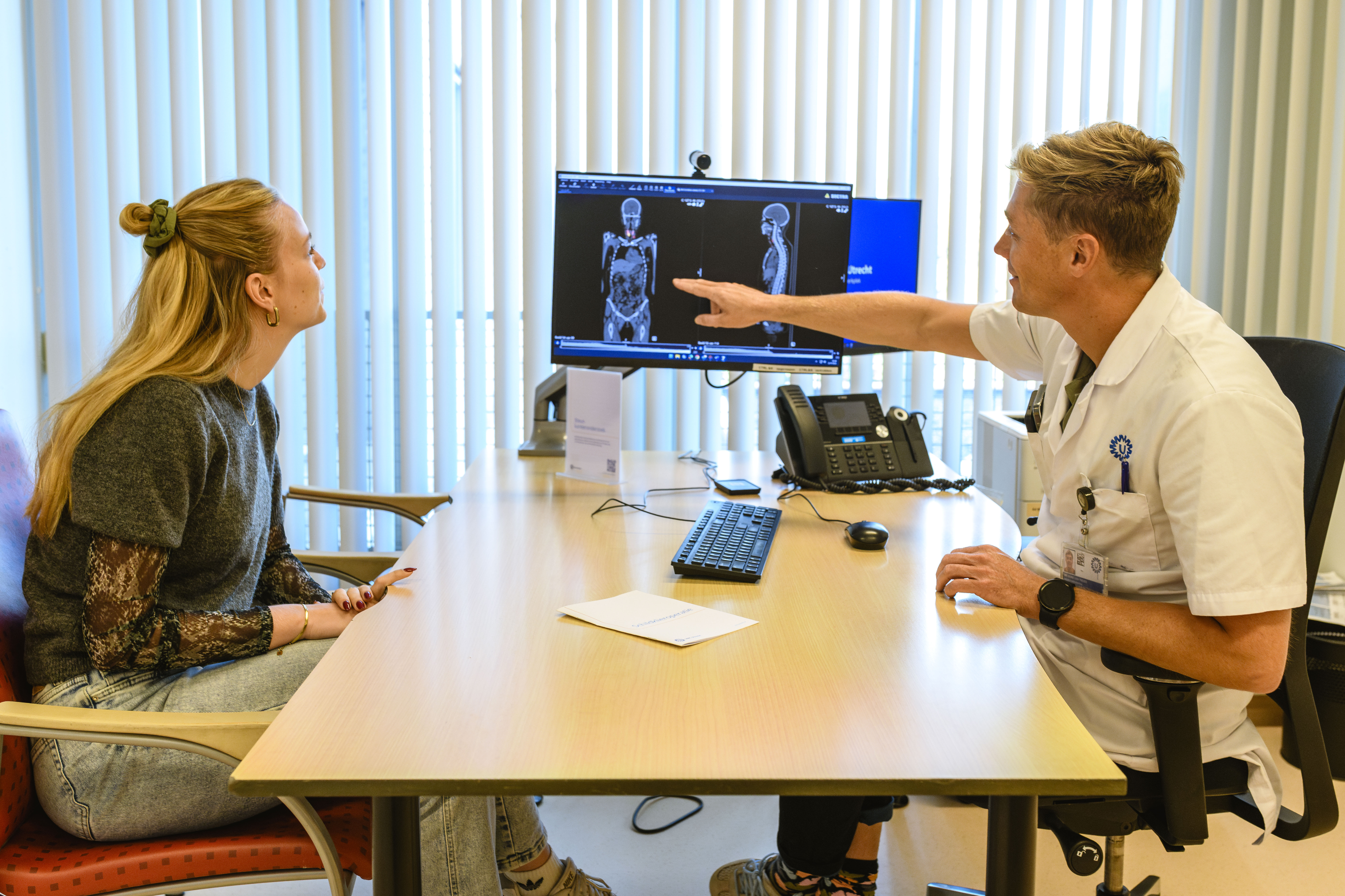 Arts bespreekt scan met jonge patiënt tijdens consult over schildklierkanker